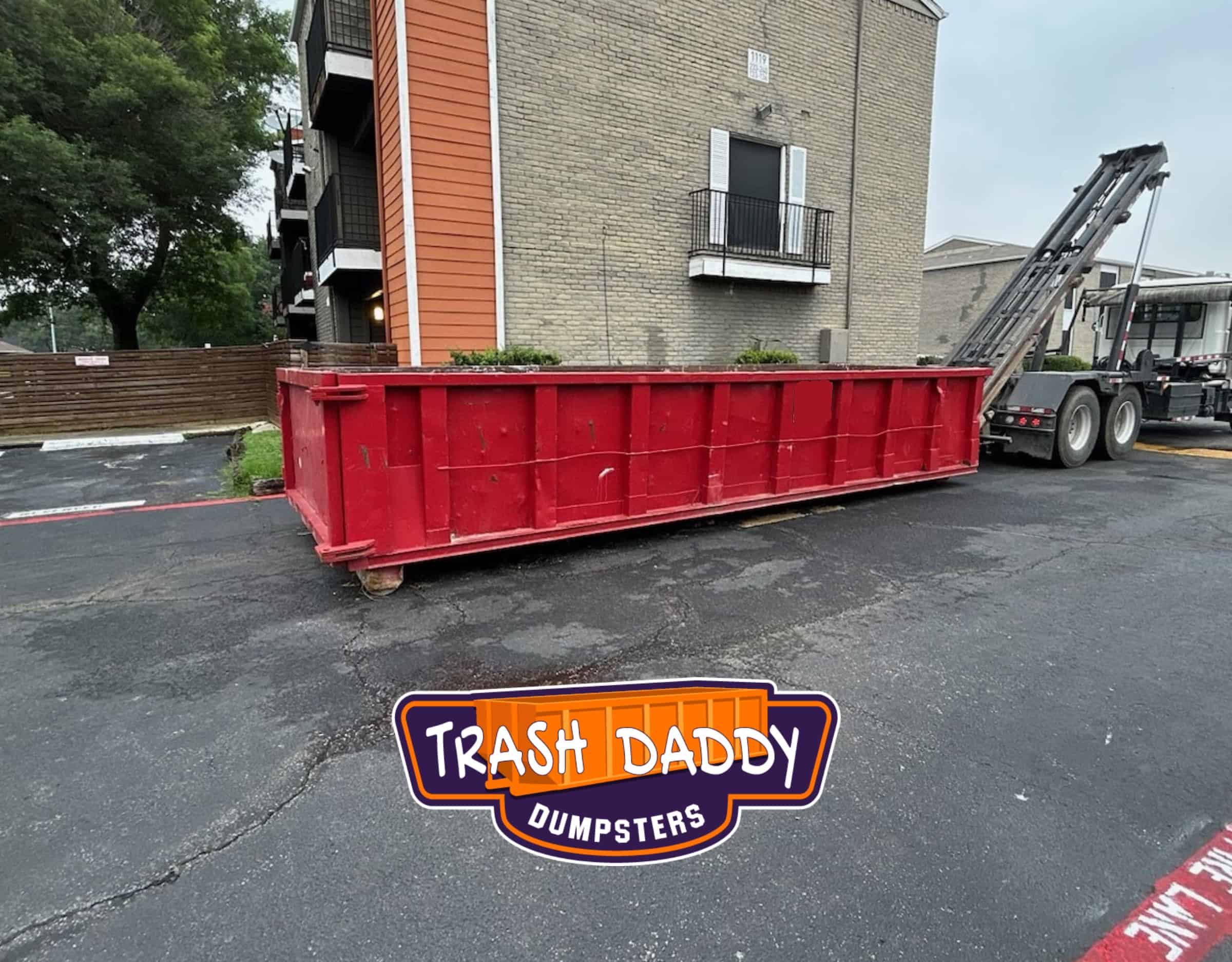 red 20 yard dumpster in apartment complex parking lot