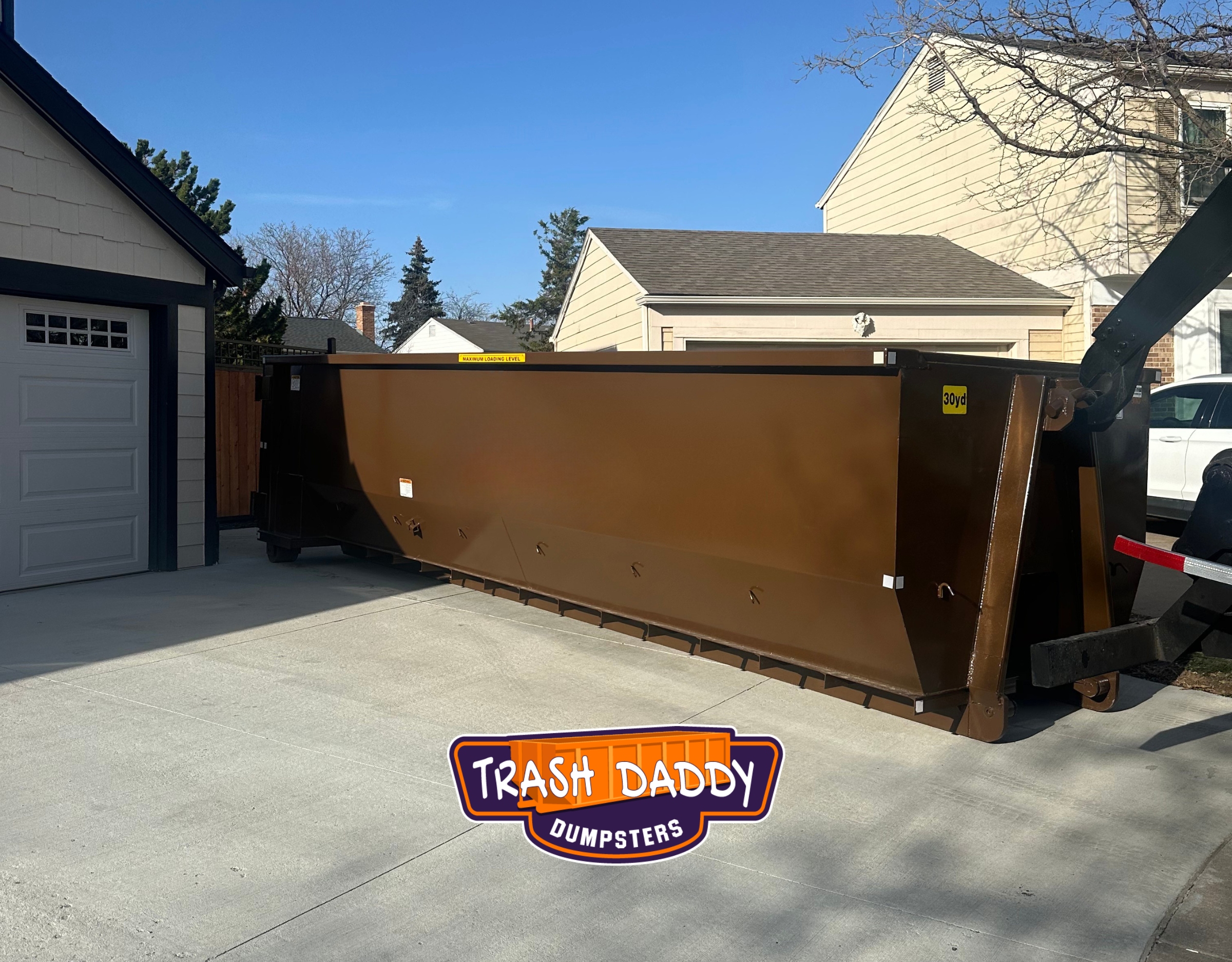 Brown 30-yard dumpster placed in a residential driveway for a home project by Trash Daddy Dumpsters.