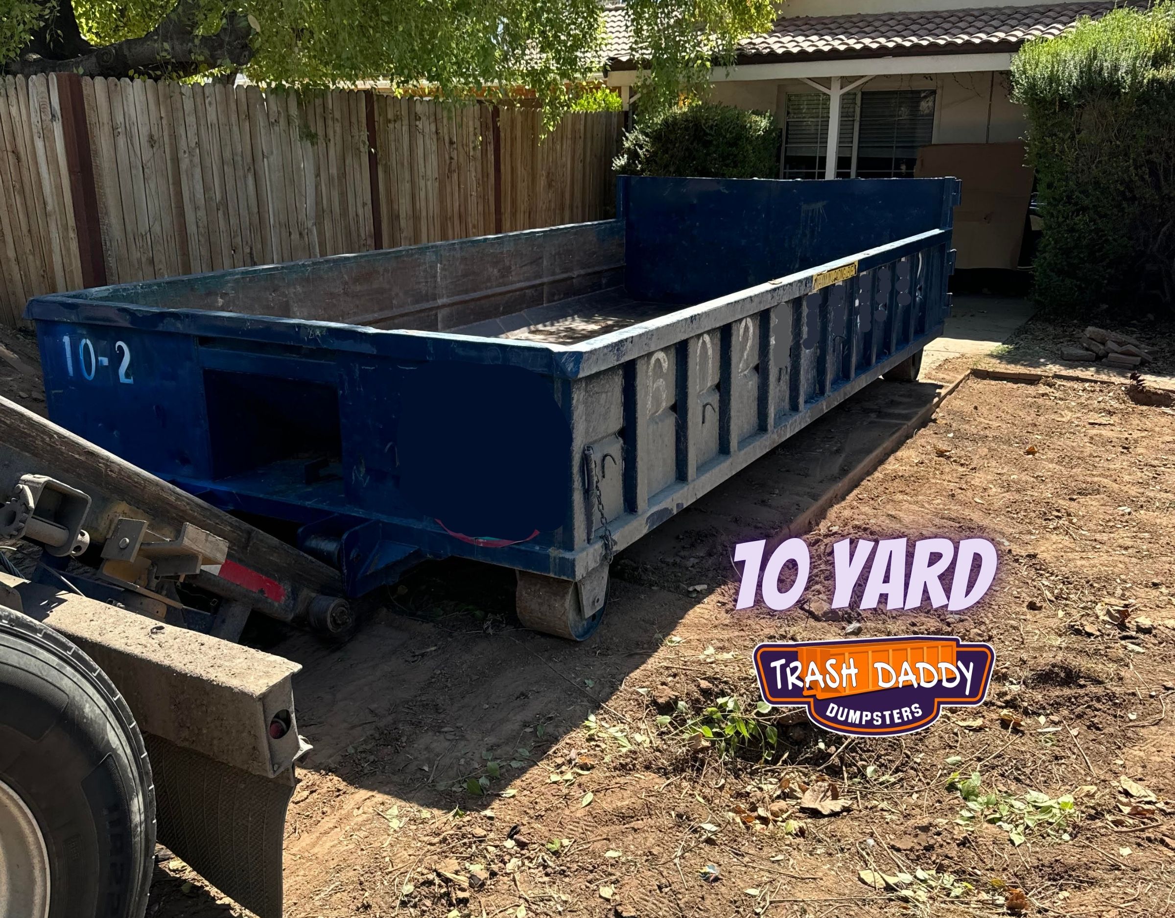 blue 10 yard roll-off dumpster dropped in a back yard