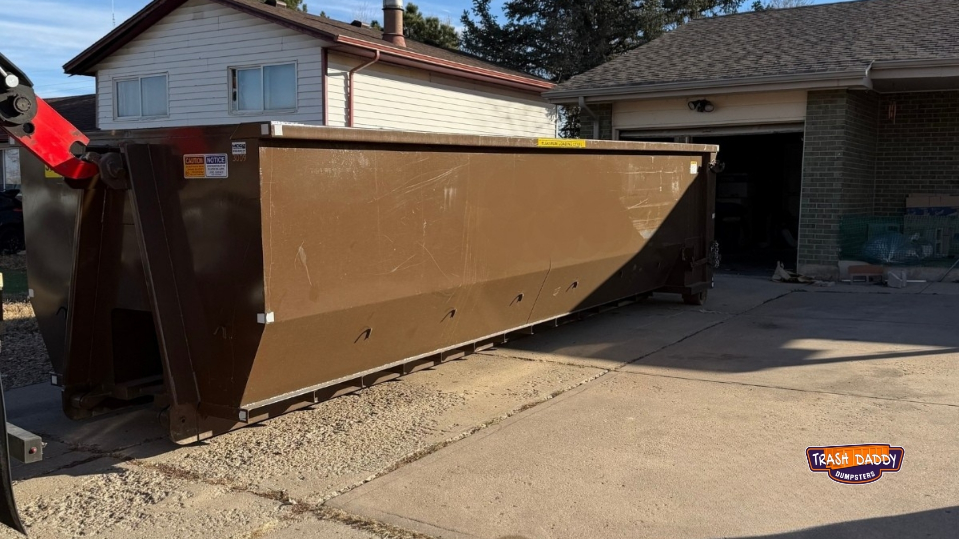 Brown 30 yard roll off being dropped in a driveway