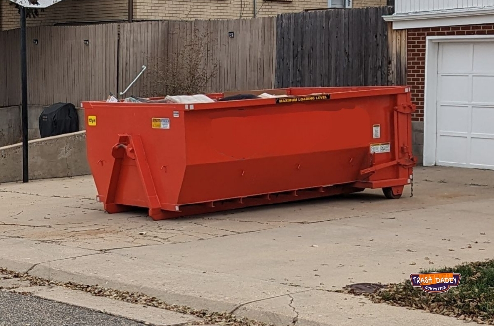 Orange 10 yard roll off dumpster in a driveway