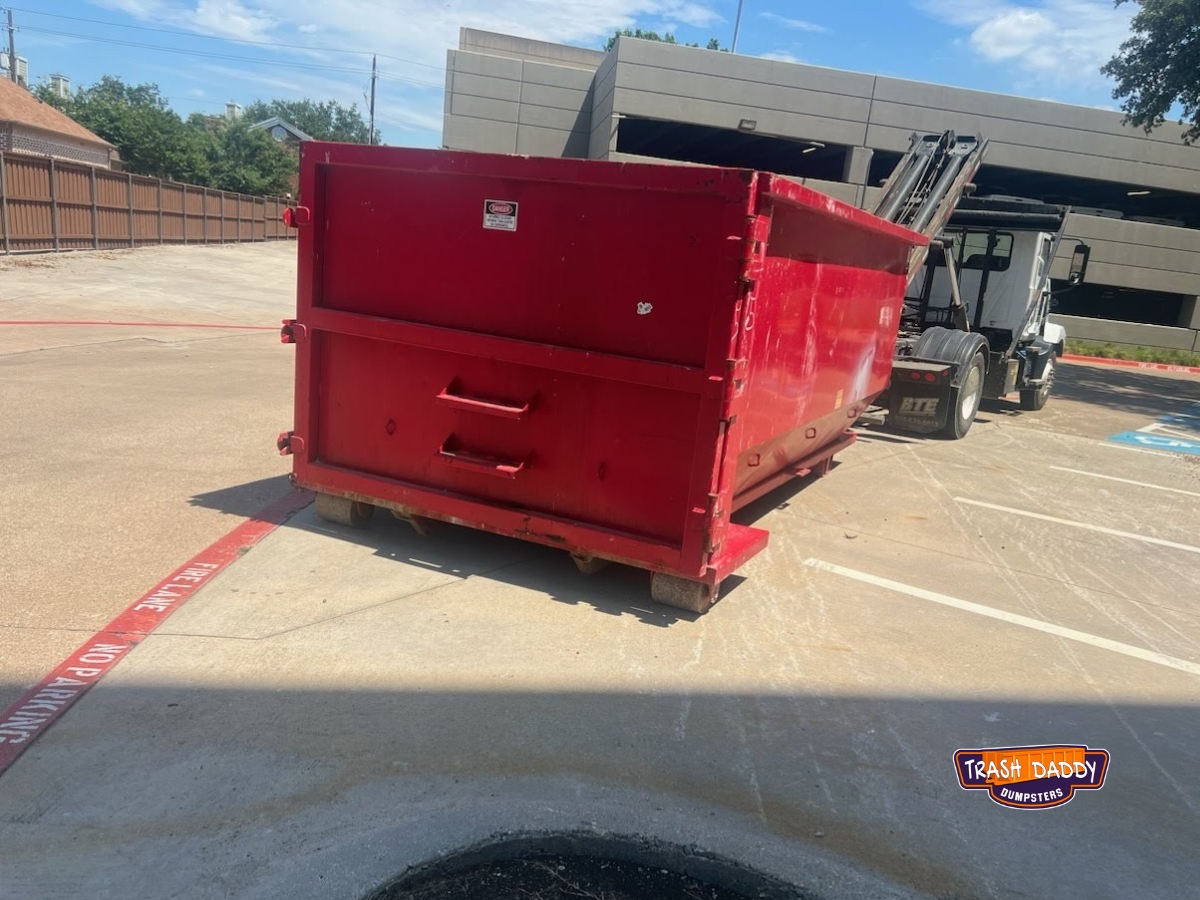Red 20 yard roll off in a commercial parking lot